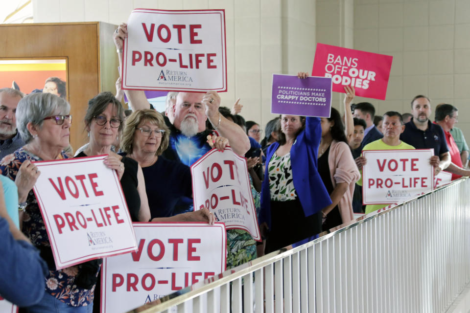 Protesters on both sides of the issue hold signs, Tuesday, May 16, 2023, in Raleigh, N.C., as they wait to enter the Senate gallery as North Carolina legislators debate on whether to override Democratic Gov. Roy Cooper's veto of a bill that would change the state's ban on nearly all abortions from those after 20 weeks of pregnancy to those after 12 weeks of pregnancy. Both the Senate and House had to complete successful override votes for the measure to be enacted into law. (AP Photo/Chris Seward)