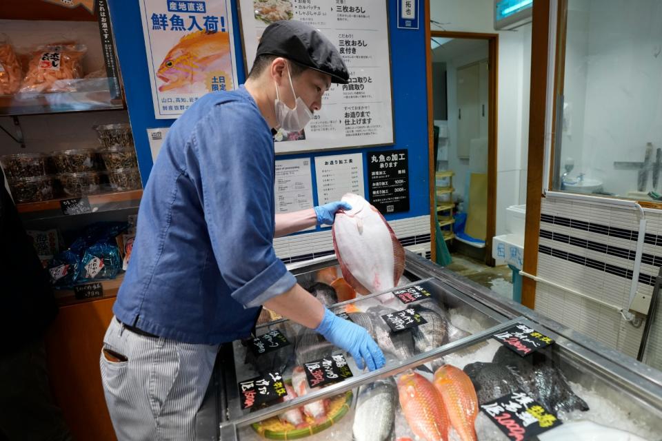 海鮮零售商Sakana Bacca的一名工作人員拿著一條來自福島的比目魚。美聯社