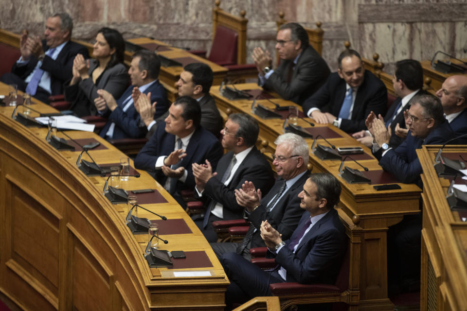 Greek Prime Minister Kyriakos Mitsotakis, front, applaud with other members of the government during a parliamentary session to vote for the new Greek President, in Athens, on Wednesday, Jan. 22, 2019. High court judge Katerina Sakellaropoulou has been elected at Greece's first female president with an overwhelming majority in a parliamentary vote. (AP Photo/Petros Giannakouris)