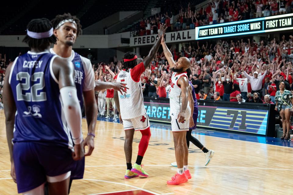 The Ville's Chris Dowe, right, holds Montrezl Harrell’s hand in the air after he made the winning free throws against Sideline Cancer on Monday night during the second round of The Basketball Tournament at Freedom Hall.