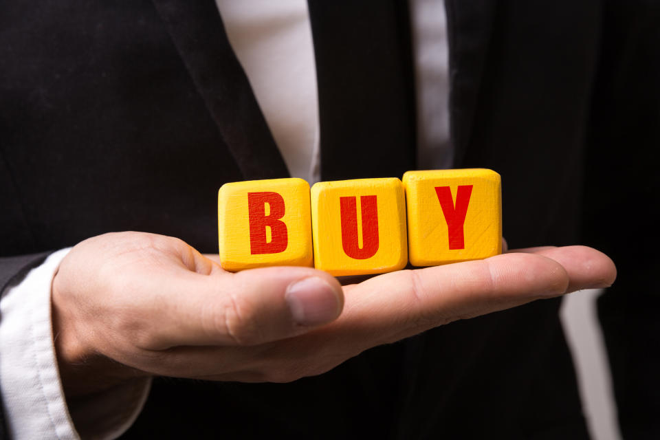 Blocks spelling out Buy on a man's hand.