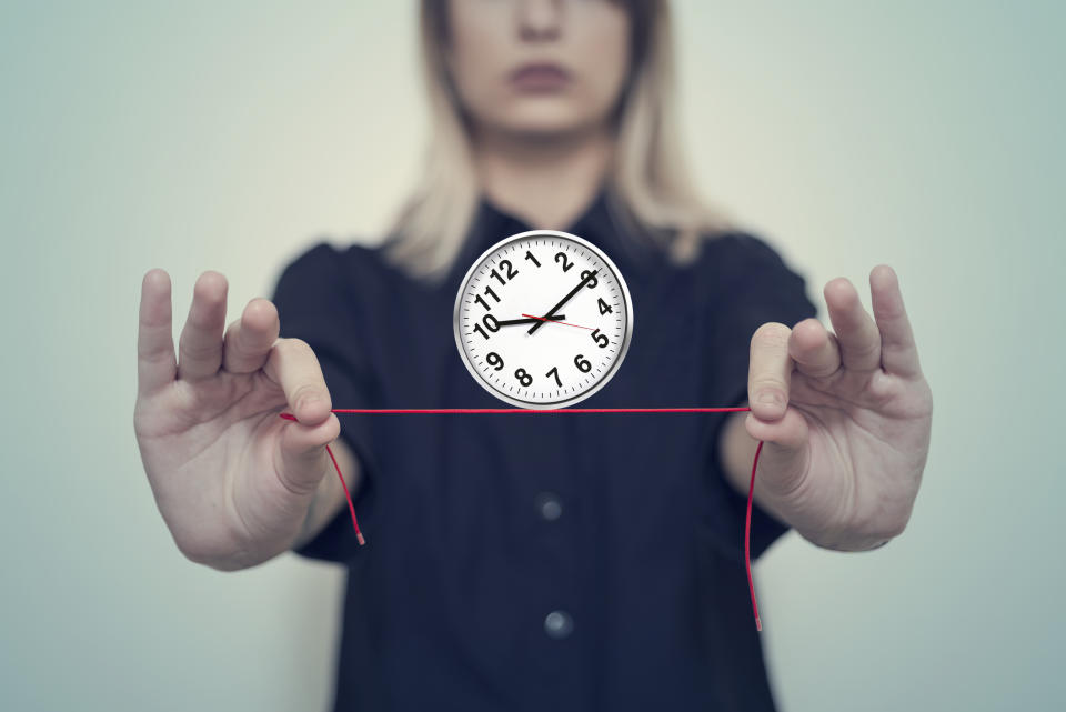 Woman's hands hold a wall clock balanced on a thread