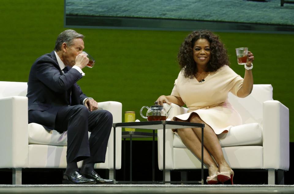 Howard Schultz, left, chairman and CEO of Starbucks Coffee Company, sits and drinks tea with Oprah Winfrey, right, to announce their partnership to offer Teavana Oprah Chai tea, Wednesday, March 19, 2014, at Starbucks' annual shareholders meeting in Seattle. (AP Photo/Ted S. Warren)