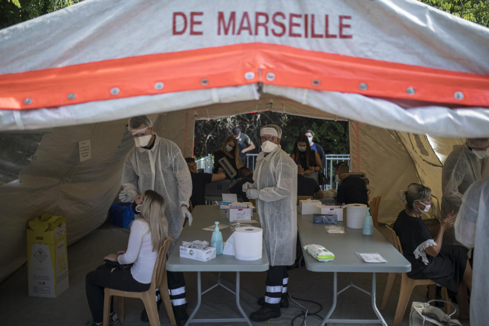 FILE - In this Sept. 24, 2020, file photo, people receive COVID-19 tests at a mobile testing center in Marseille, France. The worldwide death toll from the coronavirus eclipsed 1 million, nine months into a crisis that has devastated the global economy, tested world leaders' resolve, pitted science against politics and forced multitudes to change the way they live, learn and work. (AP Photo/Daniel Cole, File)