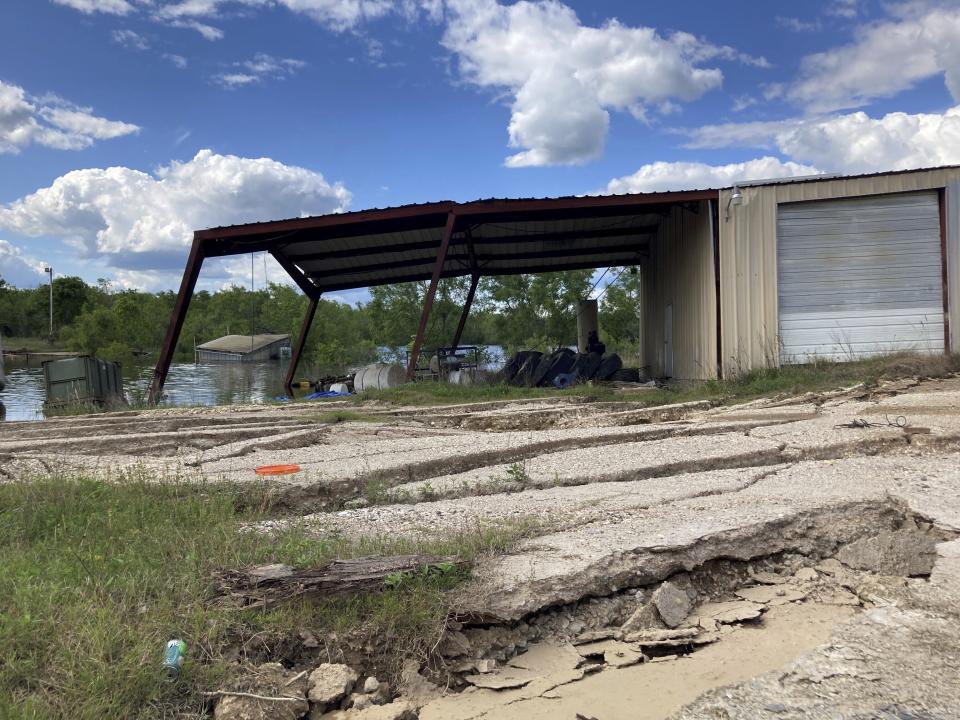 Cracks and other damage caused by a sinkhole in Daisetta, Texas, can be seen around a shuttered oil and gas waste well business located next to the opening in the ground, Tuesday, April 11, 2023. Earlier this month, Daisetta officials announced the sinkhole, which had first emerged in 2008 but had been dormant since then, had started to again expand. Officials say they're monitoring the new growth and keeping residents informed. (AP Photo/Juan A. Lozano)