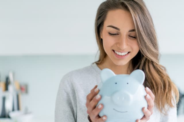 Happy woman saving money in a piggybank