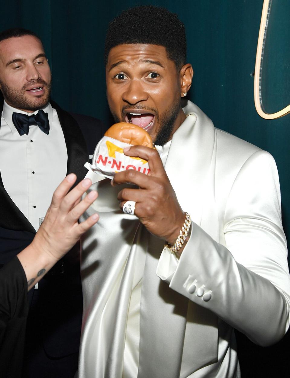Usher takes a bite out of an In-N-Out burger (do we think he ordered it Animal Style?) at the 2020 Vanity Fair Oscar Party 