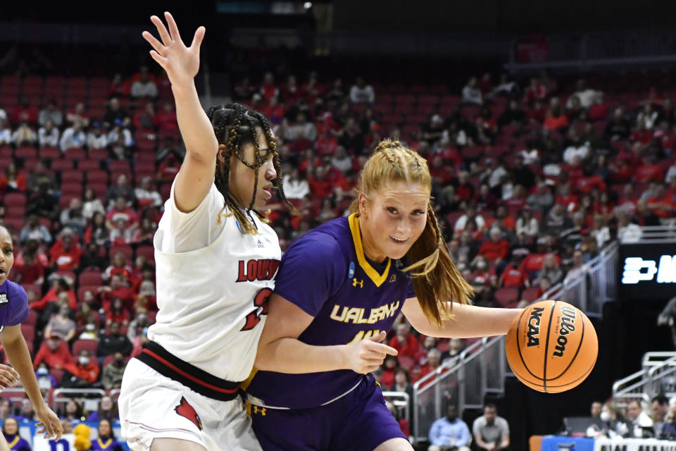 Albany guard Grace Heeps (14) tries to get past Louisville guard Chelsie Hall (23) during the first half of their women's NCAA Tournament college basketball first round game in Louisville, Ky., Friday, March 18, 2022. (AP Photo/Timothy D. Easley)