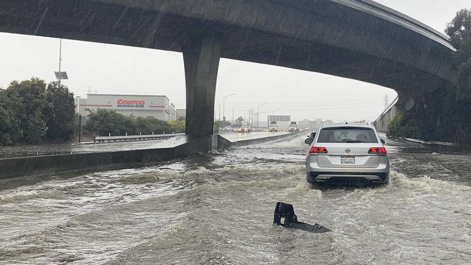 A car drives through flooded lanes on Highway 101 in South San Francisco on Dec. 31, 2022. / Credit: Jeff Chiu / AP