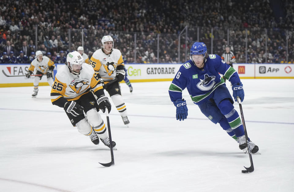 Vancouver Canucks' Brock Boeser (6) skates with the puck past Pittsburgh Penguins' Erik Karlsson (65) during the third period of an NHL hockey game Tuesday, Feb. 27, 2024, in Vancouver, British Columbia. (Darryl Dyck/The Canadian Press via AP)
