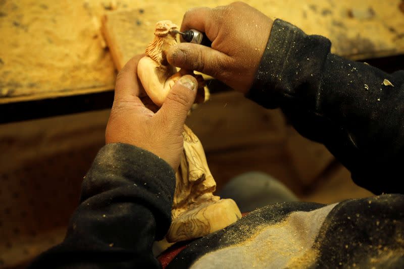 A Palestinian worker carves a figurine from olive wood to be sold during Christmas season, at a workshop in Bethlehem in the Israeli-occupied West Bank