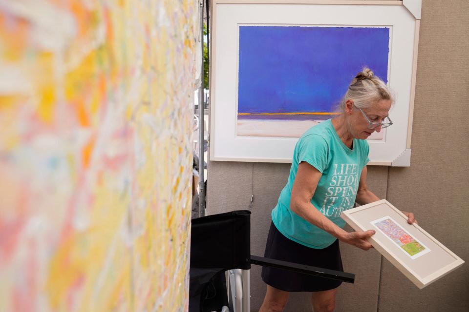 Karin Wagner Coron, of Ann Arbor, prepares her booth at the Ann Arbor Art Fair in Ann Arbor on Wednesday, July 19, 2023. The 3-day fair features almost 1,000 artists and draws in close to half a million attendees each year. Wagner Coron is a mixed-media artist and has been coming to the Ann Arbor Art Fair since 1992.