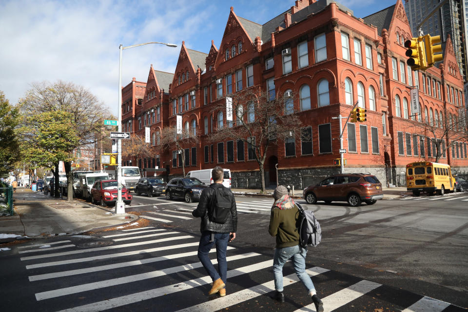 People cross the street next to the MOMA PS1 art museum located in Long Island City near the site for a proposed Amazon headquarters in the Queens borough of New York, Friday, Nov. 16, 2018. While some residents are optimistic about Amazon moving into their neighborhood, others have doubts about whether they will be able to get any of the thousands of jobs the company is promising to bring to the area. (AP Photo/Mark Lennihan)