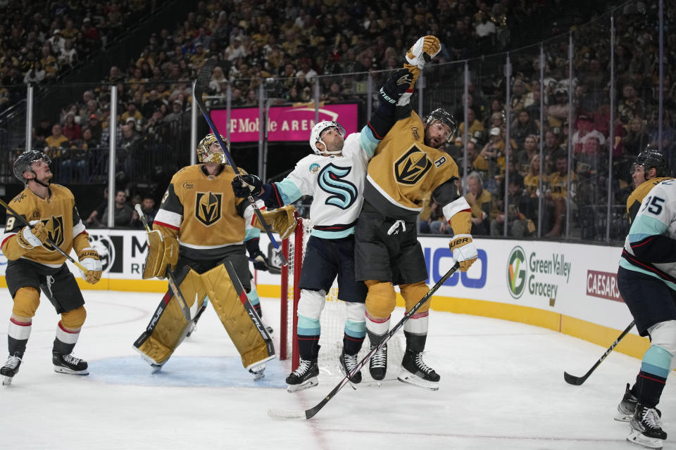 Vegas Golden Knights defenseman Alex Pietrangelo, right, and Seattle Kraken right wing Jordan Eberle try to knock the puck out of the air during the first period of an NHL hockey game Tuesday, Oct. 10, 2023, in Las Vegas. (AP Photo/John Locher)
