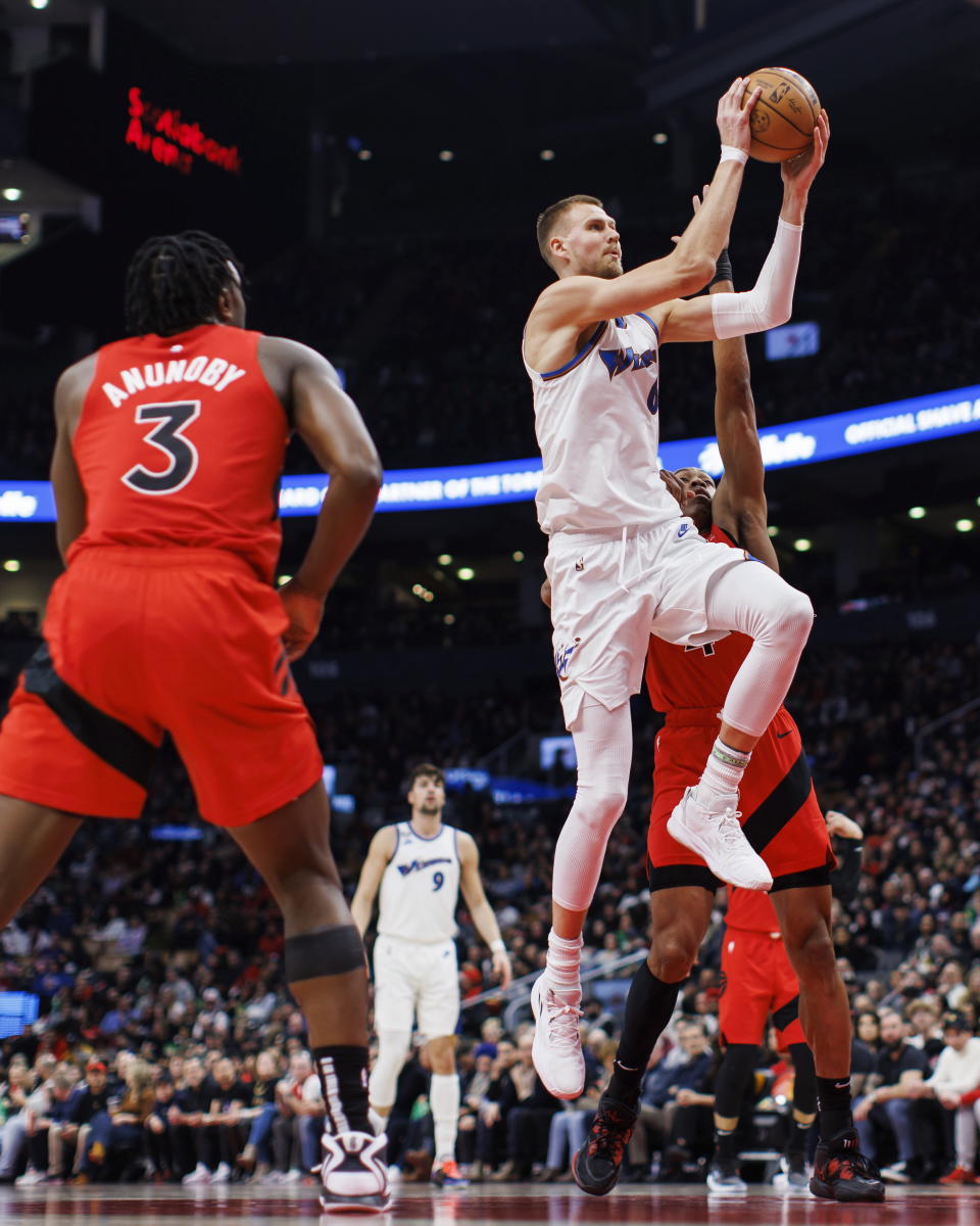 Washington Wizards center Kristaps Porzingis (6) drives to the net past Toronto Raptors forward Scottie Barnes (4) during the first half of an NBA basketball game in Toronto, Sunday, March 26, 2023. (Cole Burston/The Canadian Press via AP)