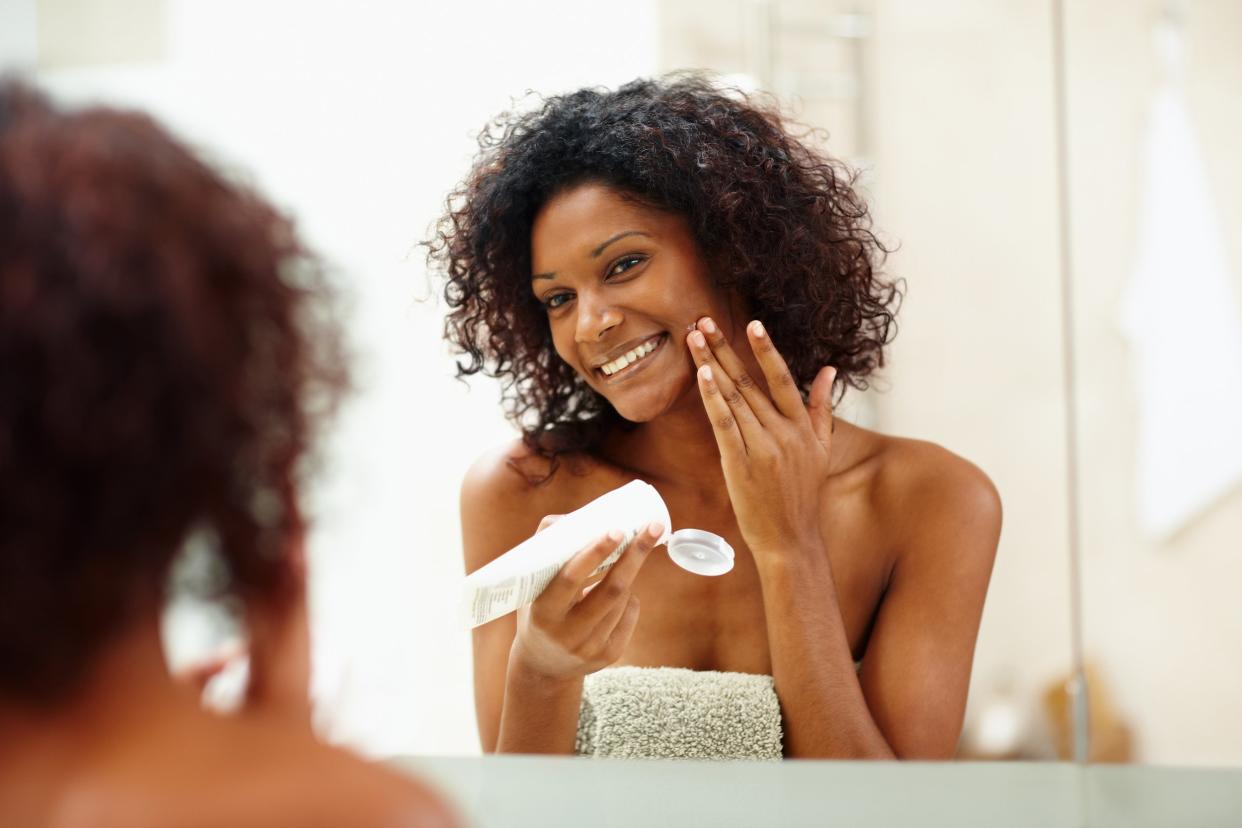 woman applying moisturizer on face in bathroom