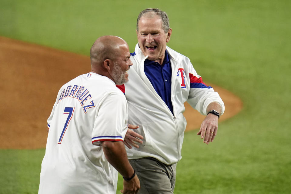 Former Preisdent George W. Bush, right, laughs with former Texas Rangers' Ivan Rodriguez after throwing out the ceremonial first pitch before Game 1 of the baseball World Series against the Arizona Diamondbacks Friday, Oct. 27, 2023, in Arlington, Texas. (AP Photo/Julio Cortez)