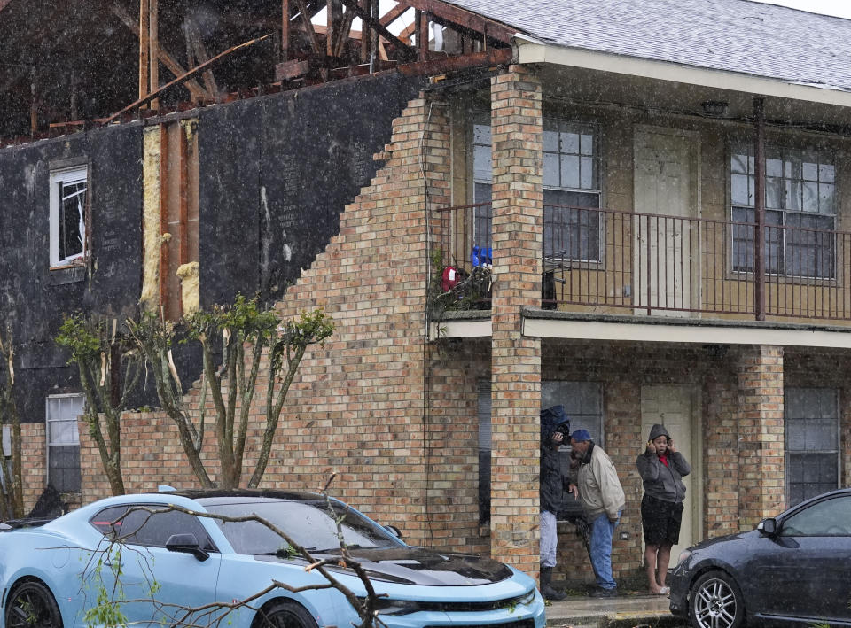 Residents of a heavily damaged apartment complex stand under an overhang in the aftermath of severe storms that swept through the region in Slidell, La., Wednesday, April 10, 2024. (AP Photo/Gerald Herbert)
