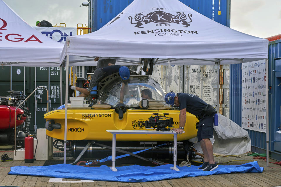 Crew inspect a submersible after a British scientist and her American pilot had to make an emergency ascent from 250 meters beneath the surface of the Indian ocean off the Seychelles after smoke filled their two-person submersible, Tuesday March 19, 2019. The pair, from the UK-led Nekton Mission investigating climate change in the region, are both safe onboard the mother ship where an electrical fire aboard the sub is being investigated as the possible cause. (AP Photo/David Keyton)