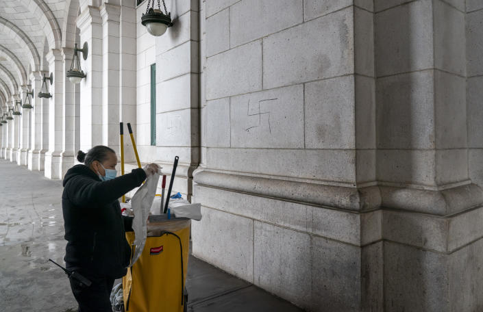 A worker prepares to cover hand-drawn swastikas on the front of Union Station near the Capitol in Washington, Friday, Jan. 28, 2022. (AP Photo/J. Scott Applewhite)