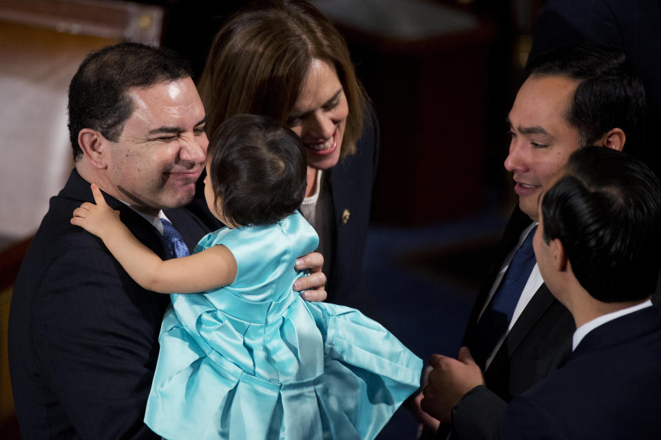 Rep. Henry Cuellar (D-Texas) holds Andrea Elena Castro, daughter of Joaquin Castro (D-Texas), second from right, before the 114th Congress was sworn in on the House floor of the Capitol on Jan. 6, 2015.