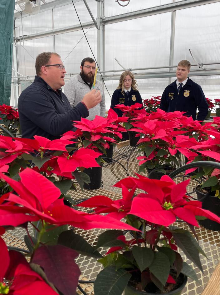 Smithville High School Agriculture Instructor Stephen Heppe explains how students in his class dealt with a pest problem after the agriculture program opened its greenhouse and received its first shipment of poinsettias.  Helping him and the students was Frank Becker (second to left), who at the time was the integrated pest management coordinator for OSU Extension, Wayne County office.  Becker is now the office's agriculture and natural resources educator and is sharing his expertise with the school's agriculture program as a guest lecturer.  Students pictured are Audrey Sidle and Ben Rhodes.