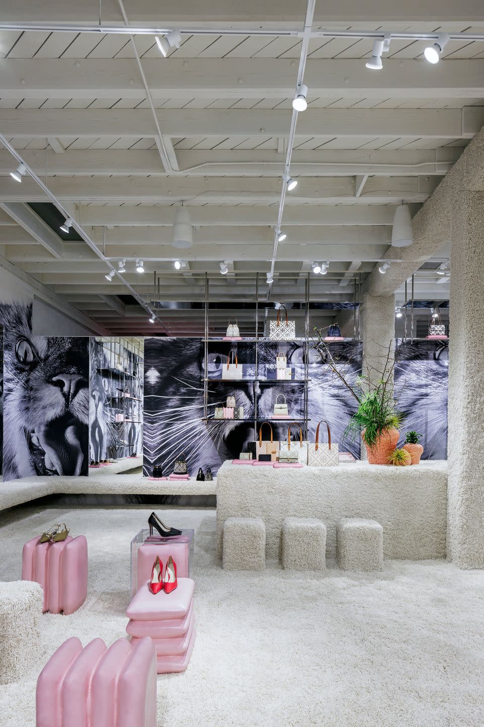 a room with a display of pink and white bags and a white table