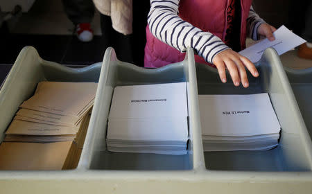 People pick ballots with the names of 2017 French presidential election candidates Emmanuel Macron and Marine Le Pen as they wait before the opening of a polling station for the second round of 2017 French presidential election in Marseille, France, May 7, 2017. REUTERS/Philippe Laurenson