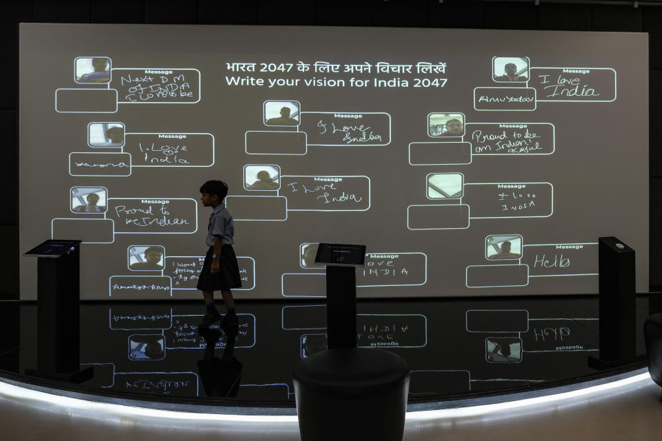 A schoolgirl walks past a screen on which visitors can write their vision for India 2047 inside "Pradhamantri Museum," or Prime Minister Museum, in New Delhi, India, Aug. 3, 2022. As India, the world’s largest democracy, celebrates 75 years of independence on Aug. 15, its independent judiciary, diverse media and minorities are buckling under the strain, putting its democracy under pressure. (AP Photo/Altaf Qadri)