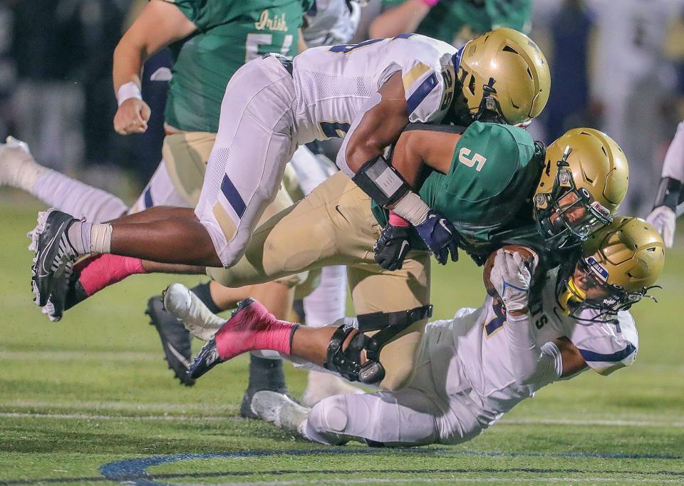 St. Vincent-St. Mary quarterback Santino Harper is taken down by Hoban's Caleb Jones, top, and Tyson Campbell on Oct. 7, 2022, in Akron.