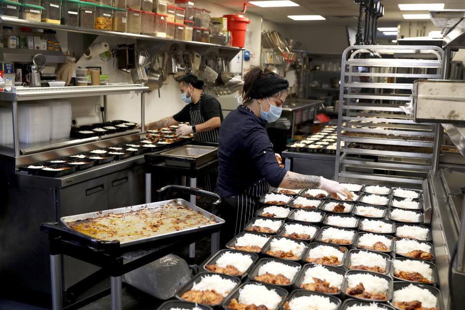 Cooks Jose Robledo, left, and Maria Cruz, prepare part of the 450 meals that ROOH restaurant owner Manish Mallick, will deliver to I Grow Chicago, in the Englewood neighborhood of Chicago, on Monday, July 13, 2020. ROOH is one of hundreds of eateries around the nation working with the non-profit organization World Central Kitchen to produce meals for the hungry. (AP Photo/Charles Rex Arbogast)