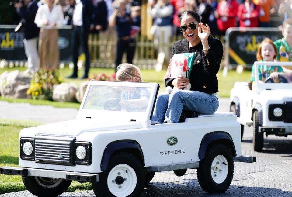 The Duchess of Sussex is driven by a child in a toy Land Rover at the Jaguar Land Rover Driving Challenge during the Invictus Games (PA) (PA Wire)