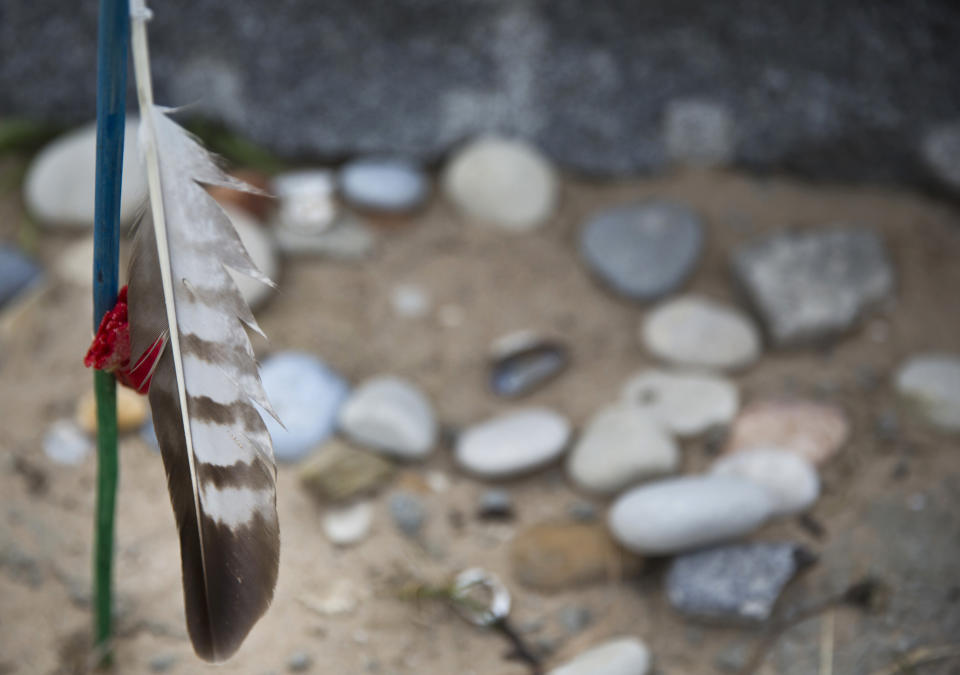 In this May 1, 2019 photo, a feather and stones are left at the Charles Shay Memorial at Omaha Beach in Saint-Laurent-sur-Mer, Normandy, France. Shay, was a medic who on June 6, 1944, landed on Omaha Beach, where he helped drag wounded soldiers out of the rising tide, saving them from drowning. (AP Photo/Virginia Mayo)