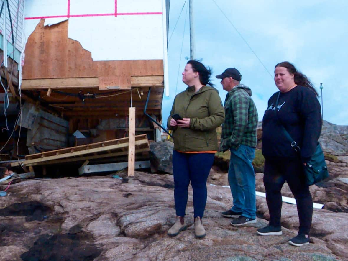 Dan Simms, centre, and daughters, from left, Dana Strickland and Donna Simms, assess the damage to their family home in Burgeo.  (Troy Turner/CBC - image credit)