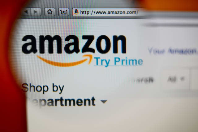 LISBON, PORTUGAL - AUGUST 3, 2014: Photo of Amazon homepage on a monitor screen through a magnifying glass.