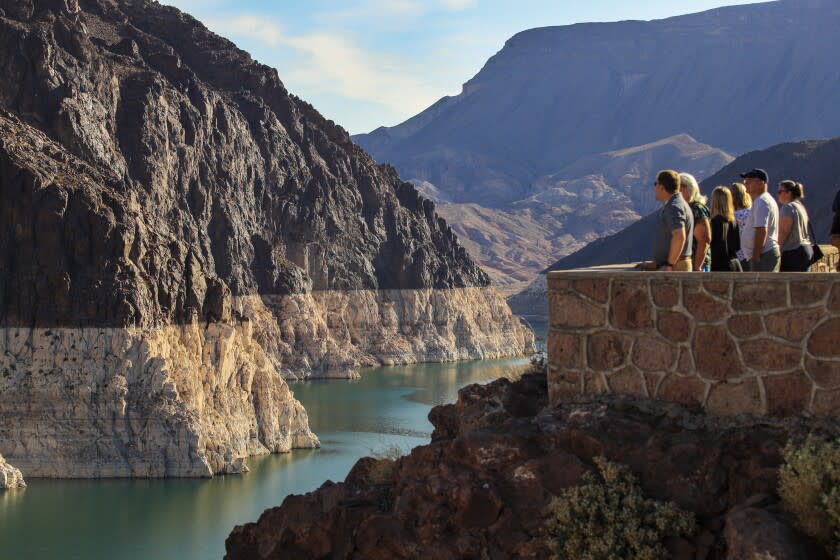 Lake Mead, NV - June 28: Tourists view the Hoover Dam and the "bathtub ring" that is visible at low water levels and is the result of the deposition of minerals on previously submerged surfaces, Lake Mead, Nevada Monday, June 28, 2021. Lake Mead is at its lowest level in history since it was filled 85 years ago, Monday, June 28, 2021. The ongoing drought has made a severe impact on Lake Mead and a milestone in the Colorado River's crisis. High temperatures, increased contractual demands for water and diminishing supply are shrinking the flow into Lake Mead. Lake Mead is the largest reservoir in the U.S., stretching 112 miles long, a shoreline of 759 miles, a total capacity of 28,255,000 acre-feet, and a maximum depth of 532 feet. (Allen J. Schaben / Los Angeles Times)