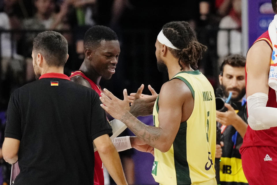 Germany guard Dennis Schroder (17), center left, and Australia guard Patty Mills (5) shake hands after Germany defeated Australia in the Basketball World Cup group E match in Okinawa, southern Japan, Sunday, Aug. 27, 2023. (AP Photo/Hiro Komae)