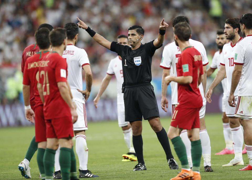 Referee Enrique Caceres is surrounded by Portuguese and Iranian players during a highly controversial game