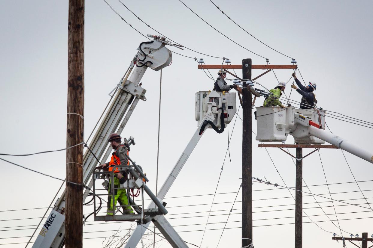 Line crews work to restore utility lines near the intersection of Main Street and Bob Straub Parkway in Springfield on Jan. 19.