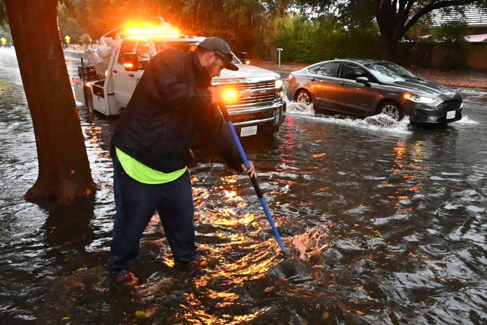 Anthony Flores, with the City of Clovis, works to clear a storm drain on Monday, Oct. 25, 2021, in Clovis, Calif. A massive storm barreled toward Southern California on Monday after flooding highways, toppling trees, cutting power to about 380,000 utility customers and causing rock slides and mud flows in areas burned bare by wildfires across the northern half of the state.