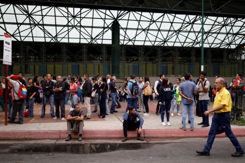 FILE PHOTO: People wait for transportation outside a closed metro station during a blackout in Caracas