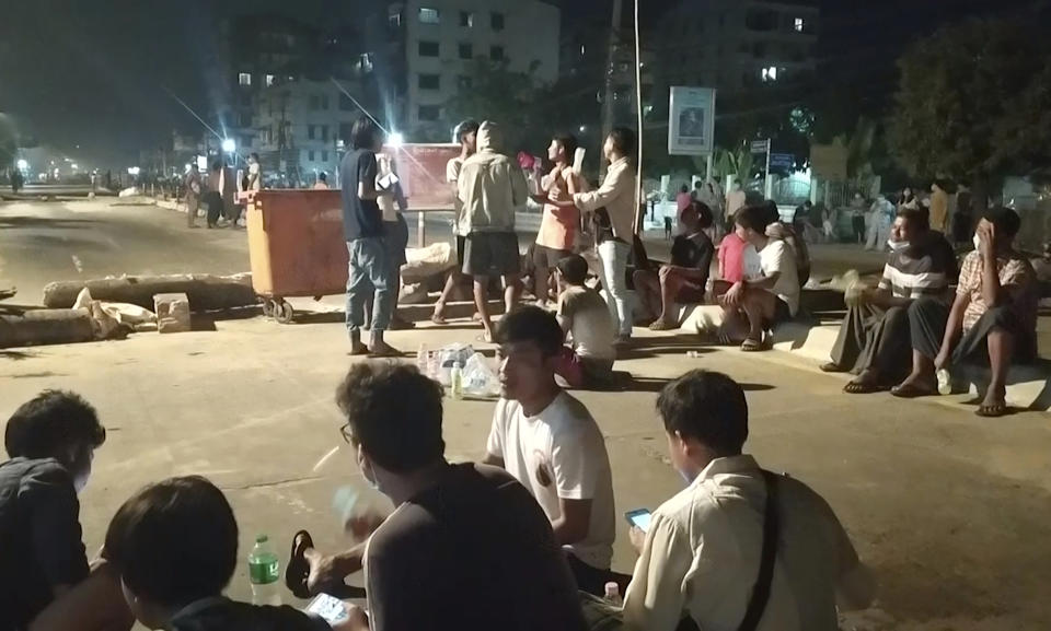 In this image taken from video, people stand outside their homes and gather together on a road in Insein township in Yangon, Myanmar, Monday, March 8, 2021. Demonstrators in Myanmar’s biggest city came out Monday night for their first mass protests in defiance of an 8 p.m. curfew, seeking to show support for an estimated 200 students trapped by security forces in a small area of one neighborhood. (AP Photo)