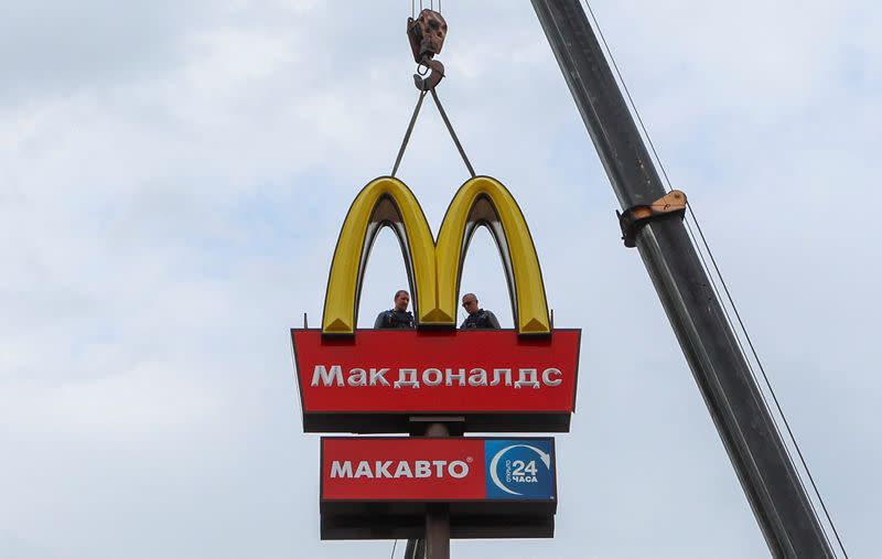 Workers remove the logo of McDonald's in Kingisepp