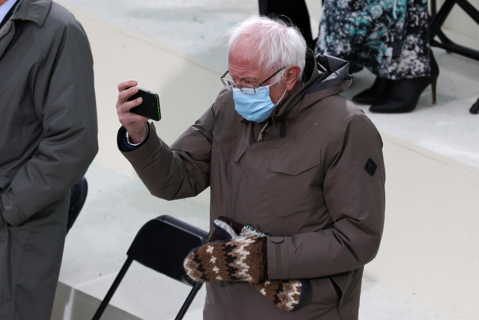 Bernie Sanders mira su teléfono en el acto de su antiguo rival político