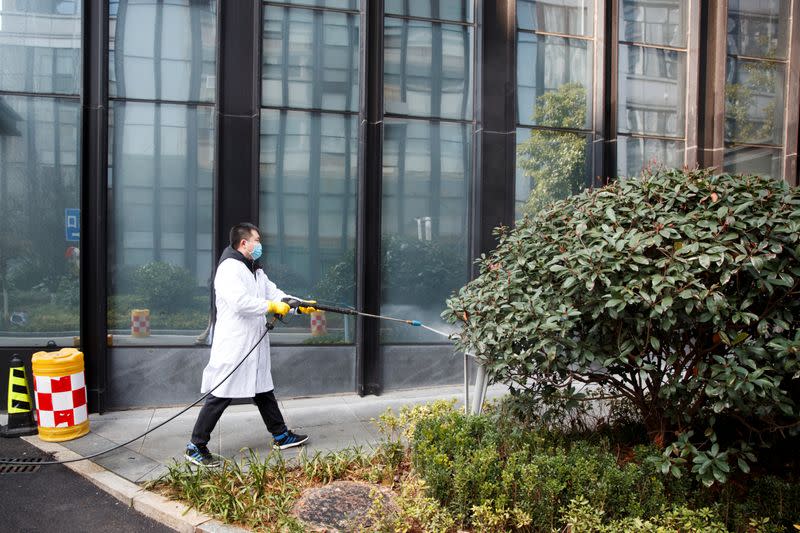 A worker sprays the pavement around an office building with disinfectant in Changsha