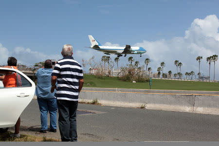 Local residents watch as Air Force One transporting U.S. President Donald Trump lands at Luis Munoz Marin International Airport, as part of a visit to the areas affected by Hurricane Maria, in San Juan, Puerto Rico October 3, 2017 REUTERS/Alvin Baez