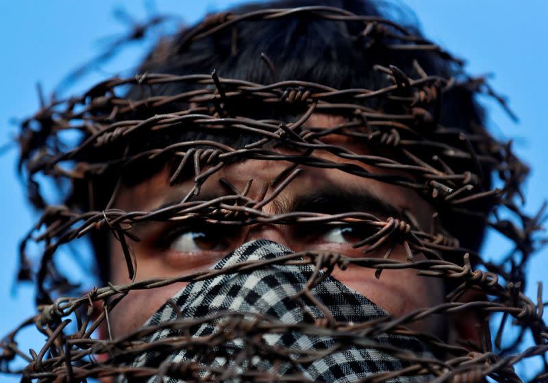 A masked Kashmiri man with his head covered with barbed wire attends a protest after Friday prayers during restrictions following the scrapping of the special constitutional status for Kashmir by the Indian government in Srinagar