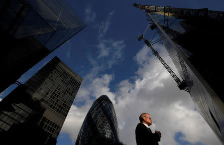 A worker walks past office skyscrapers in the City of London financial district, London, Britain, January 25, 2018. Picture taken January 25, 2018. REUTERS/Toby Melville