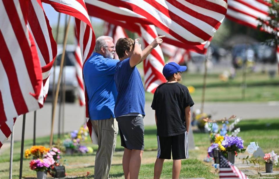 Doug Cutts, left, points where six family members who served in the military are buried as he arrives for the 60th VFW Memorial Day Service held at Fresno Memorial Gardens Monday, May 29, 2023 in Fresno.