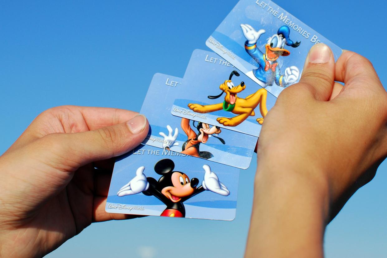 Hands holding up Disney theme park tickets